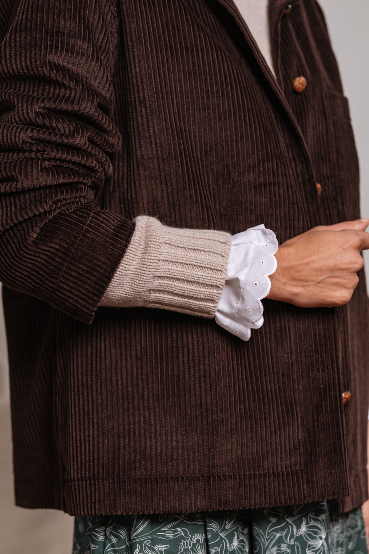 Dettaglio giacca marrone in velluto a coste di cotone con maniche lunghe e finiture sartoriali.