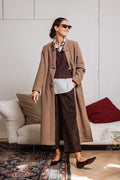 Cappotto lungo beige tortora da donna con alamari, indossato con pantaloni marroni in velluto – Paglia Milano.