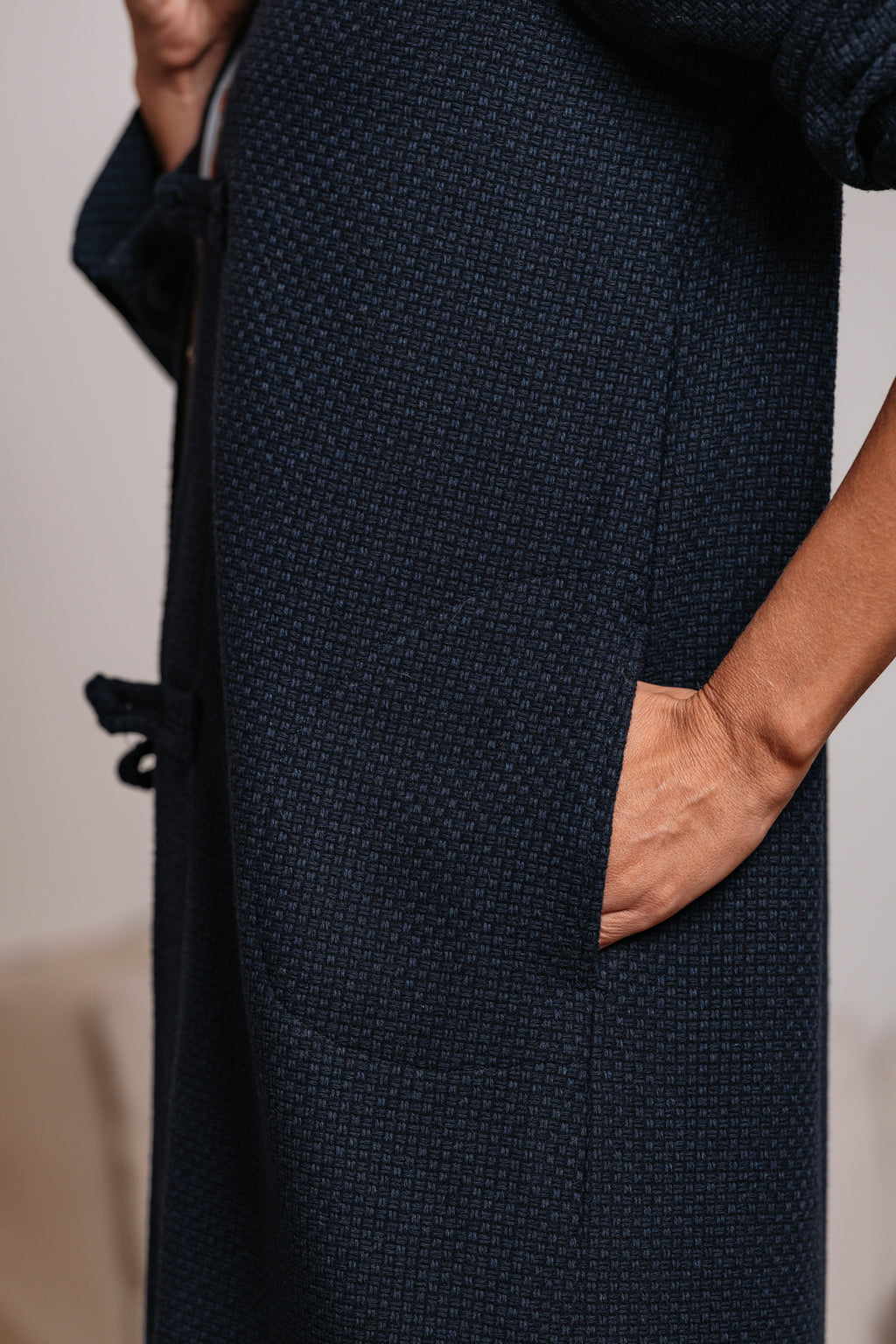 Primo piano della trama intrecciata blu e della tasca laterale del cappotto.