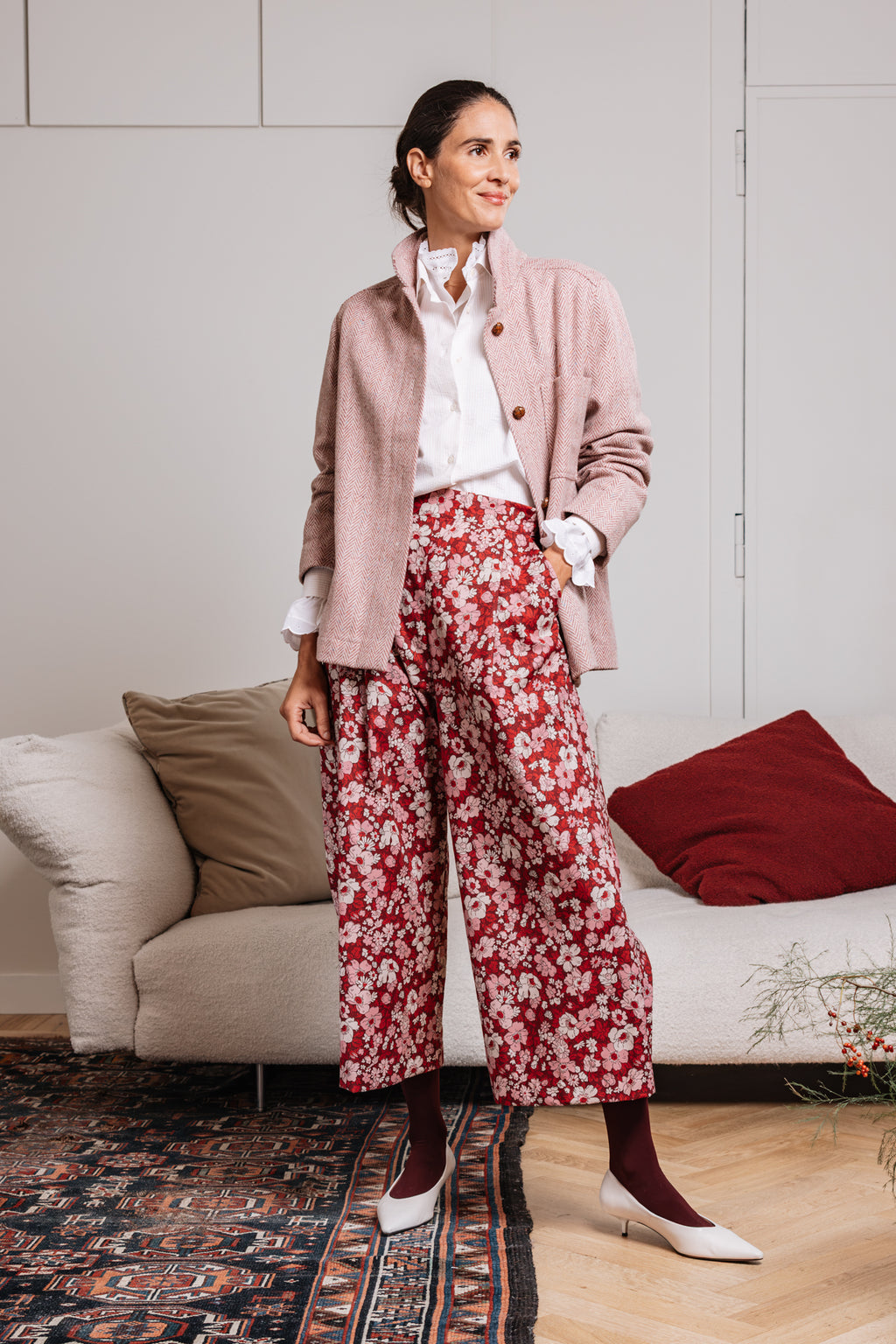 Look donna con pantalone floreale rosso a vita alta, camicia bianca e giacca rosa.